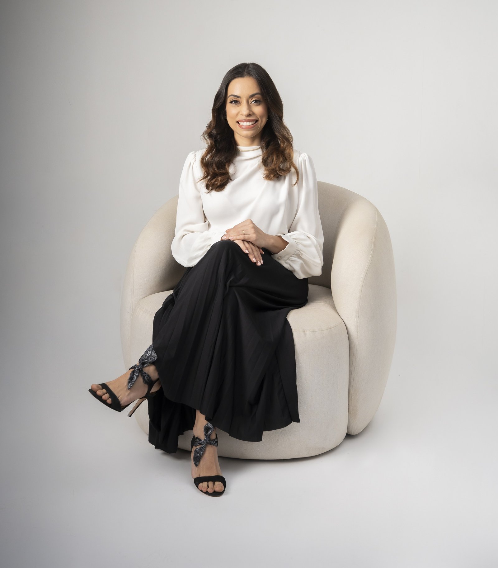Dra. Aline Letícia Pedrosa, psiquiatra online, sentada em poltrona com expressão acolhedora